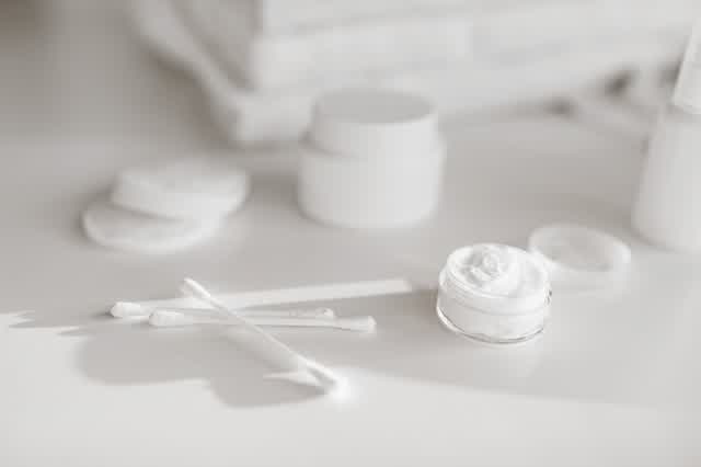 Minimal white skincare jars with cotton pads
